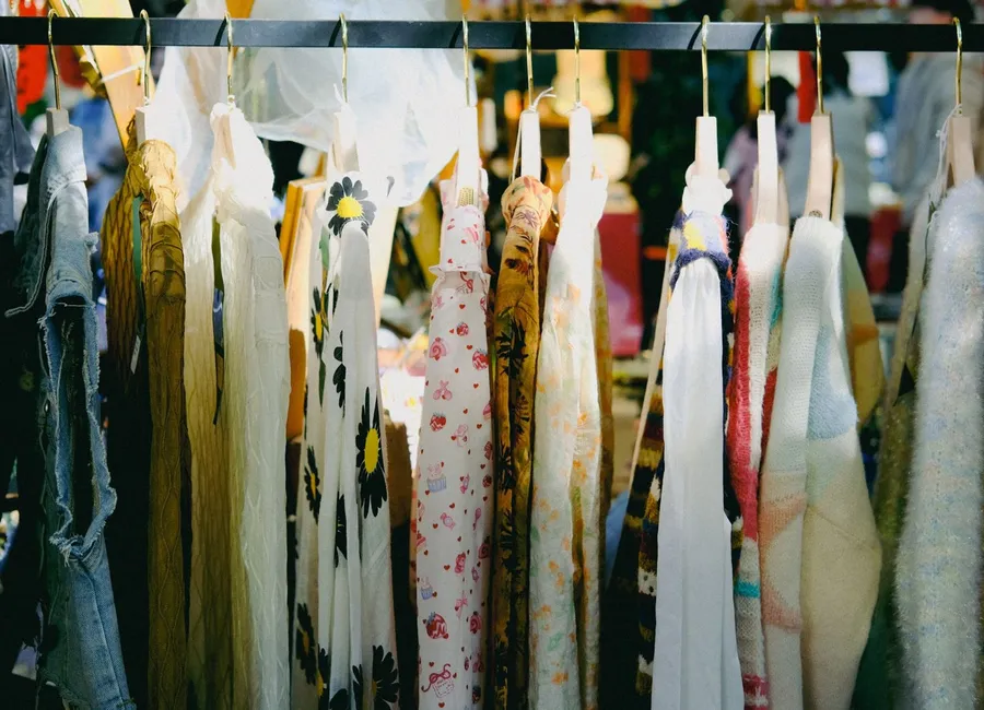 Étal de vide-grenier vintage à Angers avec vêtements, sacs et bijoux anciens exposés sur des tréteaux.